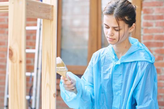 woman painter in protective clothing painting wood interior. High quality photo