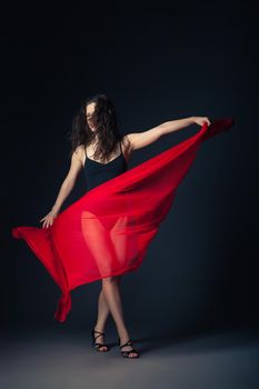 Modern style dancer with red fabric posing on a studio grey background