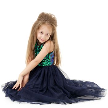 Beautiful little girl is sitting on the floor in the studio. The concept of a happy childhood, beauty and fashion. Isolated on white background.