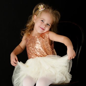 Beautiful little girl, studio portrait on a black background. The concept of a happy childhood, style and fashion.