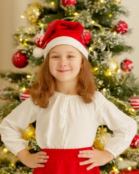 Beautiful little girl near the Christmas tree. The concept of family holidays, children's emotions.