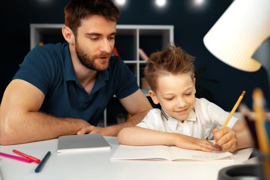 Dad and son doing school homework together sitting at the table