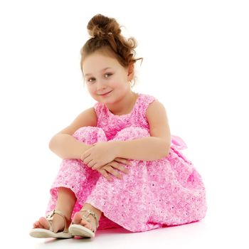 Cute girl posing on the floor in the studio. Hugs his knees. Isolated on white background. The concept of beauty and fashion