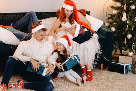 Close-up portrait of a happy family sitting on a sofa near a Christmas tree celebrating a holiday.