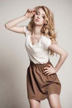 Portrait of beautyful posing blond woman with long curly hair on white background