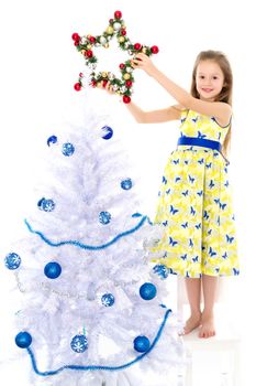 A happy little girl is decorating a Christmas tree. The concept of holidays, Christmas and New Year. Isolated on white background.