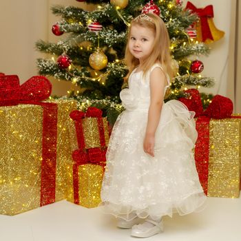 Beautiful little girl near the Christmas tree. The concept of family holidays, children's emotions.