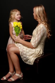 Two beautiful little girls with flowers in the studio. The concept of happy people, children.