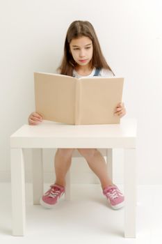 Little girl with book. The concept of education in school or kindergarten.