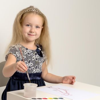 A little girl paints with paint and brush. The concept of children's creativity, happy childhood. Isolated on white background.