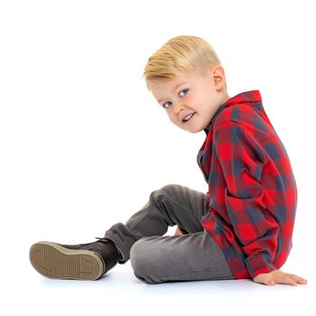 Cute little boy is sitting on the floor on a white background. The concept of a happy childhood, the harmonious development of the child in the family. Isolated.