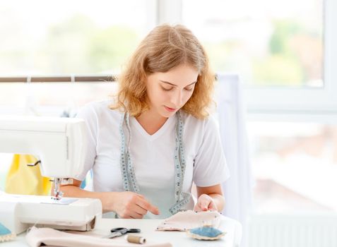 Diligent dressmaker sewing new design by hands indoors