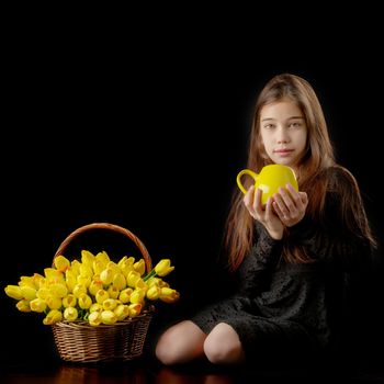 Beautiful little girl with a bouquet of tulips, studio photo on a black background. The concept of happy people, childhood.