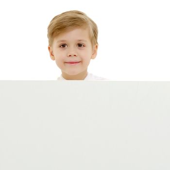 A little boy looks through an empty banner on which you can write any text. The concept of a happy childhood and advertising of children's goods. Isolated on white background.