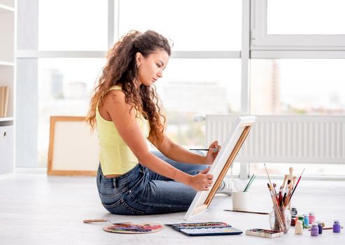 Talented young artist making picture in workroom