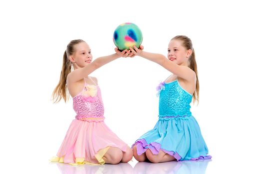 Two cheerful little girls gymnasts in competitions, perform exercises with the ball. The concept of children's sports, fitness, healthy lifestyle. Isolated on white background.