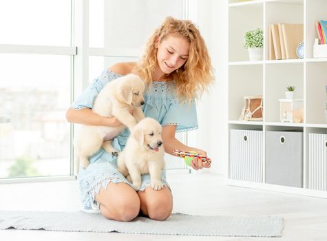 Happy girl teaching puppies to sit at home