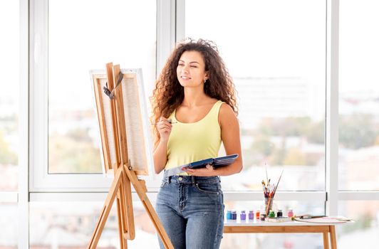 Lovely painter near easel in atelier