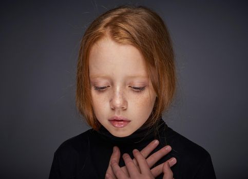 red-haired girl with freckles on her face in a black sweater posing. High quality photo