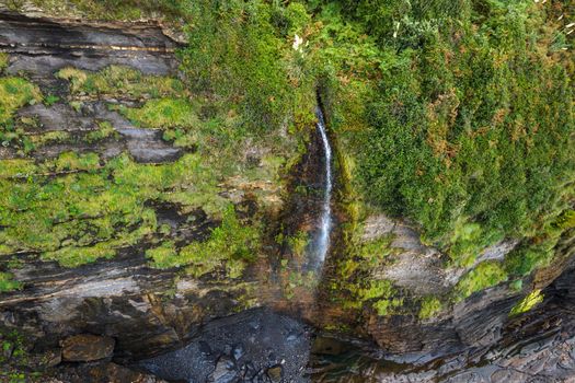 Aerial view of an idyllic waterfall at tropical coastline scenery. High quality photo.