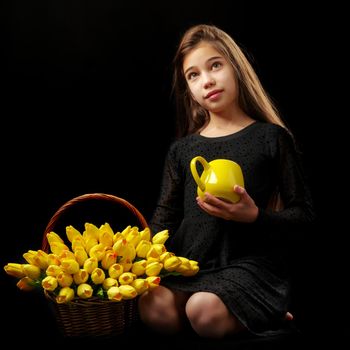 Beautiful little girl with a bouquet of tulips, studio photo on a black background. The concept of happy people, childhood.