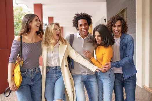 Multi-ethnic group of friends walking together on the street while chatting and having fun.