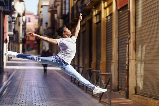 Young black man doing an acrobatic jump in the middle of the street. Cuban guy.