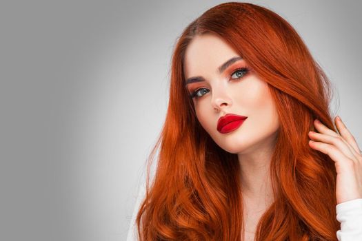 Glamour woman with long red hair on gray background