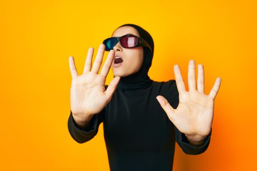 cheerful woman in black hijab popcorn 3D glasses cinema yellow background. High quality photo