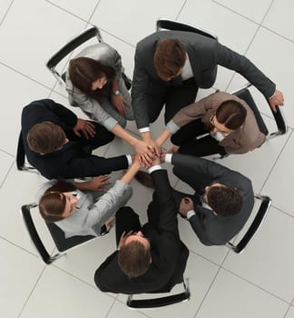 top view.a group of employees with their hands folded together.the concept of teamwork