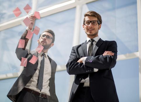 Business colleagues read stickers pasted on a transparent glass wall. business concept