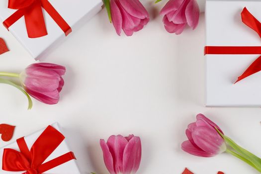 Flat lay valentines day frame with pink tulips red hearts and gift boxes on a white background