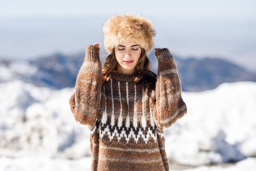 Beautiful woman enjoying the snowy mountains in winter, in Sierra Nevada, Granada, Spain. Female wearing winter clothes.