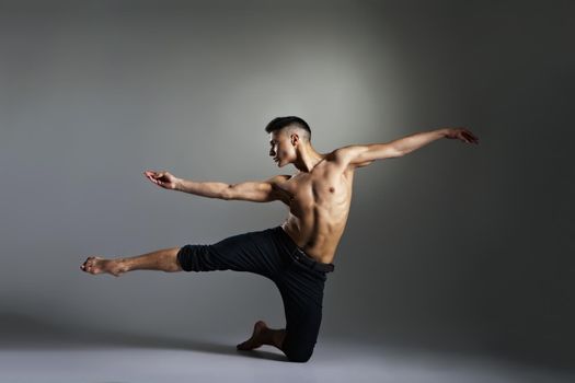 Young and stylish modern ballet dancer on grey background