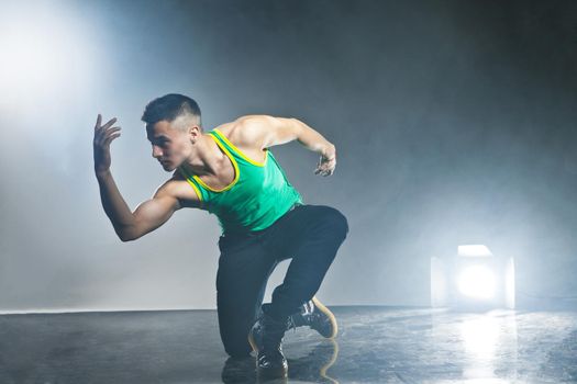 Modern style dancer posing on dark background with flashes and smoke