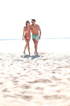 Happy fun beach vacations couple walking together laughing having fun on travel destination.