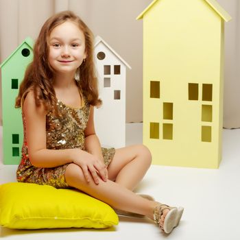 A cute little girl is playing with wooden houses. The concept of family happiness, play, creative development of the child.