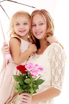 Two beautiful little girls with flowers in the studio. The concept of happy people, children.