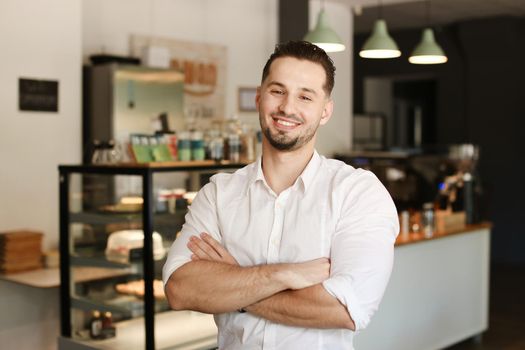 Young male administrator standing with at cafe, wearing white shirt. Concept of business and success.