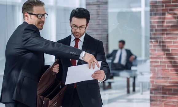 business partners discuss the document standing in the office lobby.the concept of business relationship