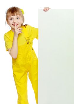 Girl with a short bangs on her head and bright yellow overalls.She crouched down on the white advertising banner.