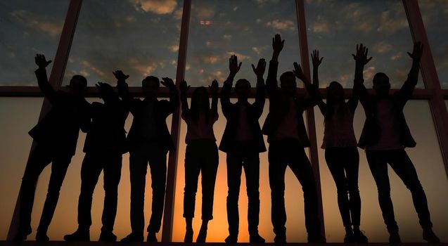 silhouette of a group of business people raising their hands .photo with copy space