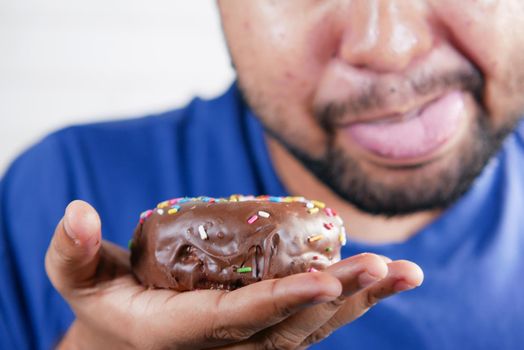 young man open his mouth eating donut , selective focus