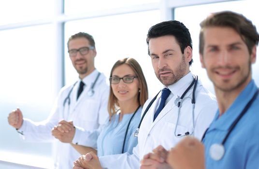 Successful team of medical doctors are looking at camera and smiling while standing in hospital
