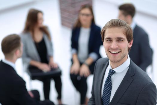 Happy businessman posing in front of his team while working on the background