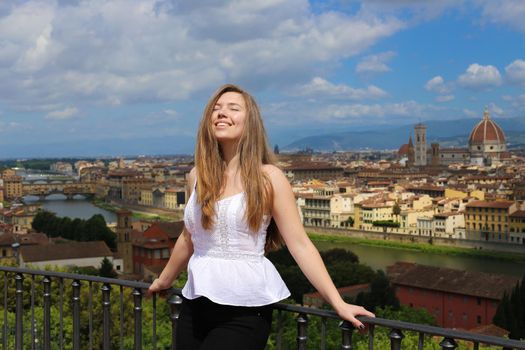 Girl standing on balcony with Florence cityscape background. Concept of last minute cheap tours to Italy and summer vacations in Europe.