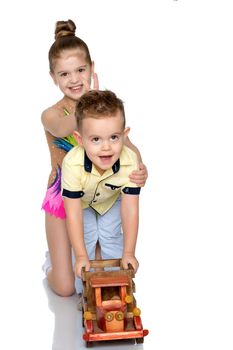 Brother and sister are playing with a toy car. The concept of happy childhood, people, harmonious development of the child in the family. Isolated on white background.