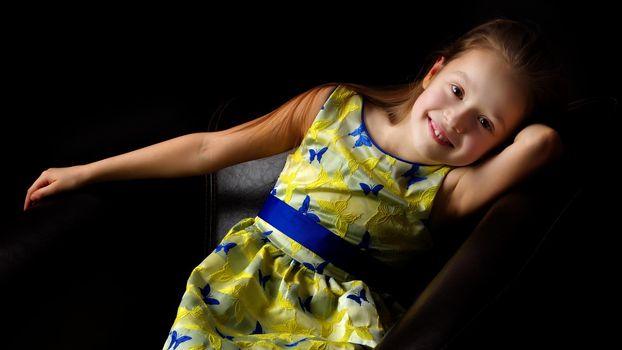 Beautiful little girl, studio portrait on a black background. The concept of a happy childhood, style and fashion.