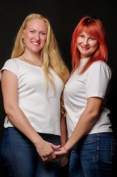 Young, beautiful women in white T-shirts are holding hands.