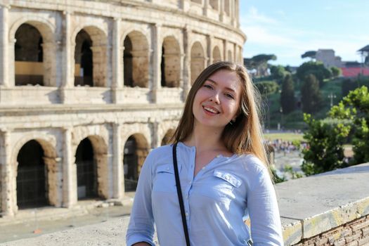 Young female tourist standing near Colosseum in Rome. Concept of last minute tours to Italy and traveling to Europe in summer vacations.